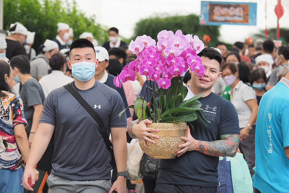 Some public members joyfully head home with elegant New Year festive flowers to usher in Chinese New Year. (Photo by Willy Ang)